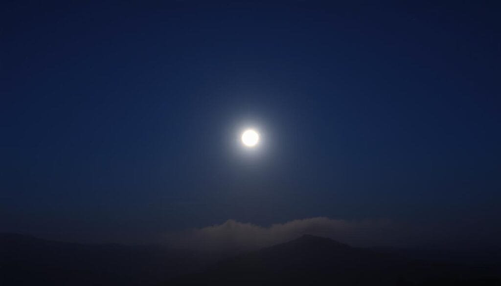 A serene evening sky, the full moon casting a soft glow over a tranquil landscape. In the foreground, an atmospheric haze gently diffuses the moonlight, creating a captivating display of dispersión de luz atmosférica. The middle ground features rolling hills or mountains, their silhouettes barely visible through the mist. The background is a deep, inky blue, dotted with a sprinkling of stars. The scene is captured through a wide-angle lens, emphasizing the vastness of the night sky and the enveloping nature of the atmospheric effects. A sense of wonder and contemplation pervades the image, inviting the viewer to ponder the enigmatic nature of the moon's appearance on the horizon.